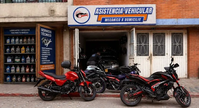 Local de Asistencia Vehicular en Fontibón: fachada con el aviso del taller, motos parqueadas al frente y un técnico trabajando sobre un vehículo.